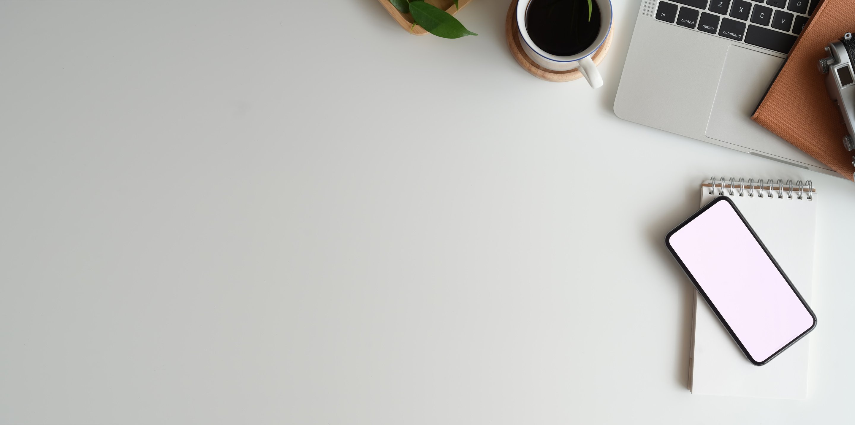 White Ceramic Cup Beside a Laptop on White Table